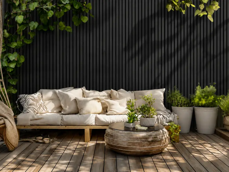 Dunkle WPC Wandverkleidung als Rückwand für eine Gartensitzecke auf Holzterrasse